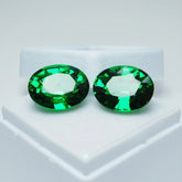 Two green gemstones on a white background