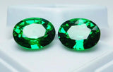 Two green gemstones on a white background