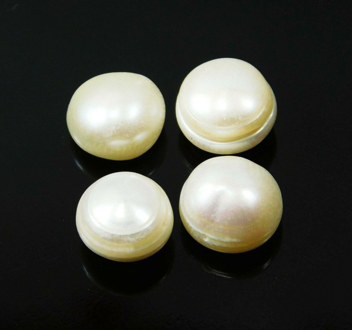 A set of four white, round Shape natural pearl gemstones against a black background.