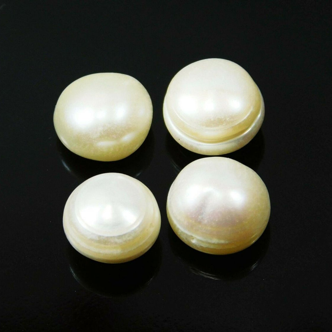 A set of four white, round Shape natural pearl gemstones against a black background.