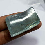 Rectangular crystal held between fingers against a white background