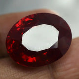 Close-up of a red gemstone held between fingers