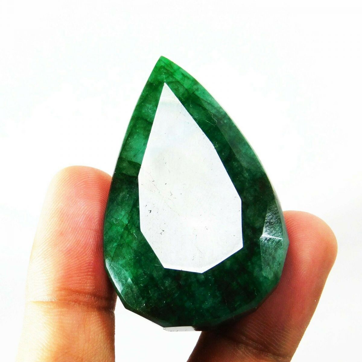 Natural Muzo Colombian emerald held upright between fingers, showcasing its vivid green hue and oversized pear shape.