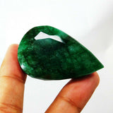 Hand-held emerald angled to the right, reflecting the handcrafted cut and deep green body of the 190.65 carat gem.