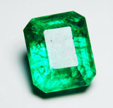 Green emerald gemstone reflecting on polished white base