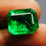 Natural emerald held delicately between two fingers