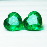 Second view of the 16 Ct green emerald heart-shaped duo against a white background, presenting their cut precision and slightly included clarity with elegant brilliance.