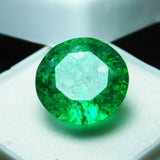 8.23 carat round Colombian emerald gemstone shimmering under bright light, showcasing vivid green tones and clarity.