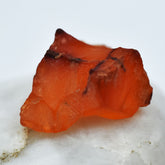 Uncut raw rough orange sapphire gemstone on a white background