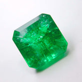 Certified Colombian emerald gemstone centered over a clean white background, highlighting its emerald cut and vivid green tone.