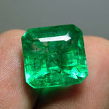 Similar finger-held view from a slightly different angle, emphasizing the gem's translucent quality.