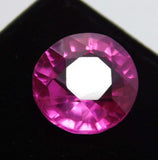 Eye-clean pink ruby gemstone, round cut, placed on black surface with white background – 8.30 carat certified stone