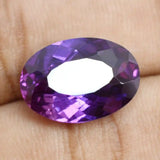 Faceted purple gemstone held between fingers