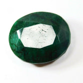 Large green oval emerald reflecting light at center, placed on neutral background highlighting its vibrant color