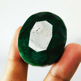 Natural 181.95 Ct green emerald gemstone placed between fingers showing side profile and thickness