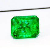 Natural green emerald gemstone with eye-clean clarity and rectangular shape viewed from top while held in fingers