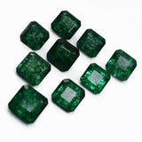 Group of nine emerald gemstones placed close together in irregular pattern – square cut, natural green stones