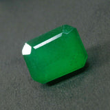 Opaque green emerald displayed on grey background with clarity