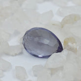 Faceted purple gemstone on a white stone background