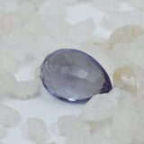 Faceted purple gemstone on a white stone background