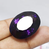 55.32 ct natural oval amethyst gemstone shown in hand