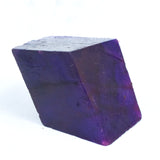 Rough uncut natural Tanzanite gemstone, deep purple 500 carat stone on white background.