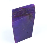 Natural Tanzanite rough uncut gemstone, 500 ct deep purple crystal on white surface.