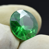 8.85 Ct Green Tsavorite Garnet held between two gloved fingers, round cut, excellent for jewelry making