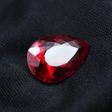 Loose red ruby gemstone placed on black background emphasizing vibrant red hue
