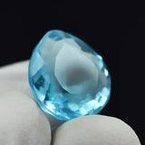 “Teardrop-cut blue crystal stone showcasing brilliance on a dark backdrop.”