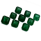 Nine square-cut emeralds on a white background