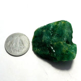 Green mineral rock next to a Russian one ruble coin on a white background