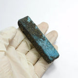 Textured blue bar held by a gloved hand on a white background