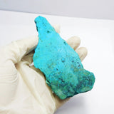 Turquoise stone held by a gloved hand on a white background
