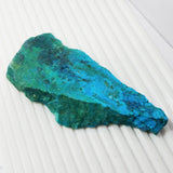 Blue-green mineral stone on a white textured surface