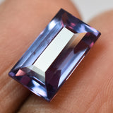 Color change Alexandrite held between two gloved fingers showing emerald cut and brilliance
