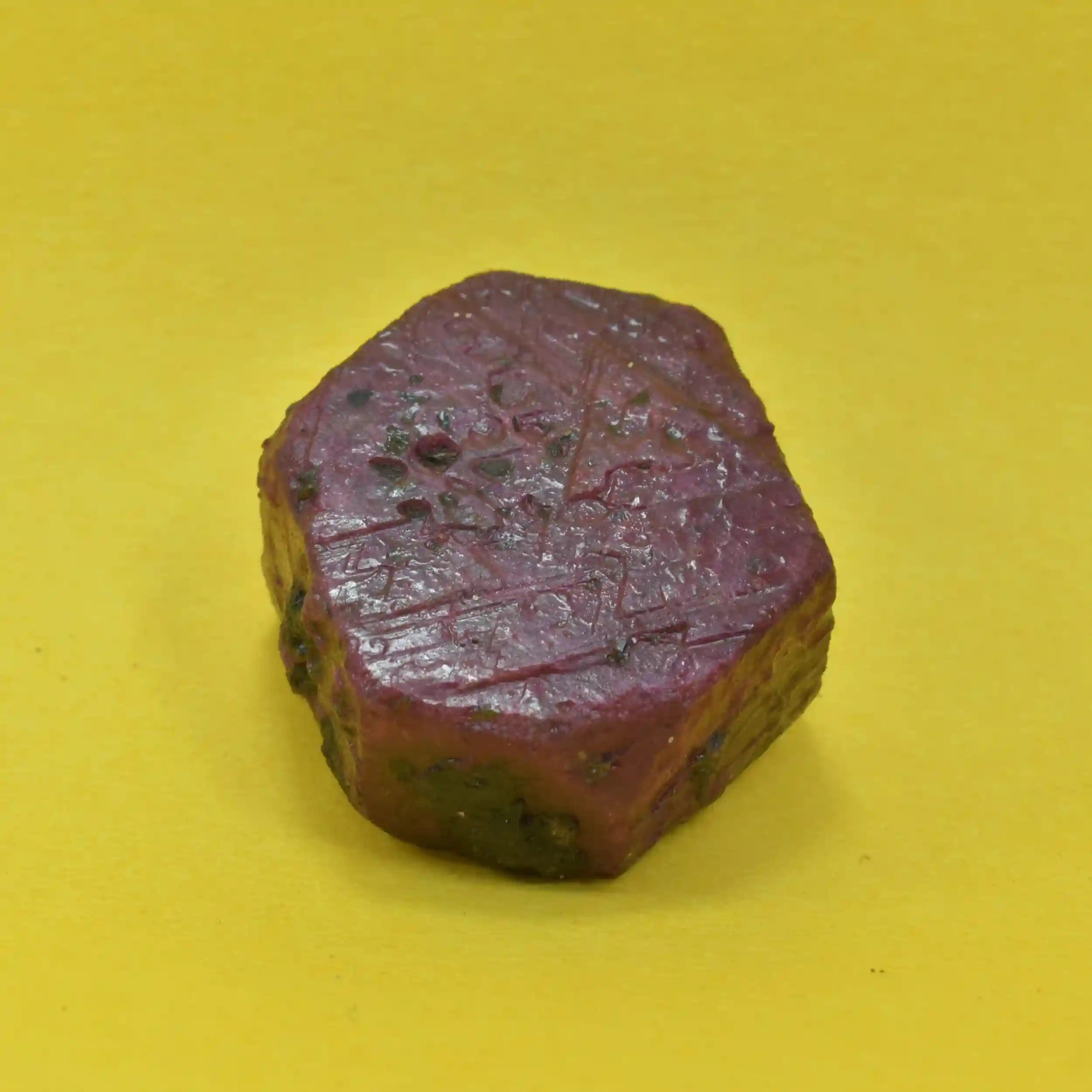Polished purple stone with engraved patterns on a yellow background