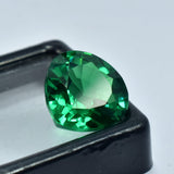 Tsavorite green garnet placed at the corner of a black-edged display lid with clear center, enhancing its shape and transparency