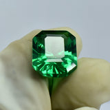 Certified emerald-cut garnet gently held between two gloved fingers, highlighting the gem’s structure and flawless finish