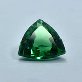 10.65 Carat Trillion Shaped Green Garnet placed on a plain white background, translucent and eye-clean