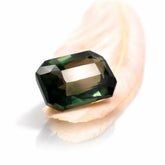 Buy Natural Green Sapphire 10.35 Ct Emerald Cut Green gemstone held by a hand on a white background