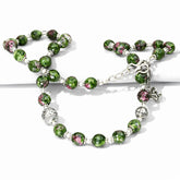 Green beaded bracelet with silver accents on a white background