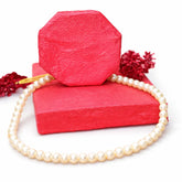 Pearl bracelet on a red textured surface with red flowers