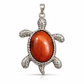 Turtle-shaped pendant with red stone and silver frame on a white background