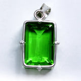 Green gemstone pendant with silver frame on a white background