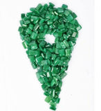 Tiny green emerald gemstones creatively arranged in a pointed oval formation resembling a location pin shape, displayed on a neutral background.