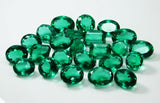 Multiple emeralds laid flat on clean white background