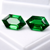 Two green hexagonal gemstones on a white background