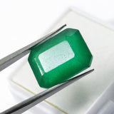 colombian emerald natural gemstone Faceted green gemstone held between tweezers on a white background