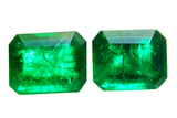 Two emerald green gemstones on a white background
